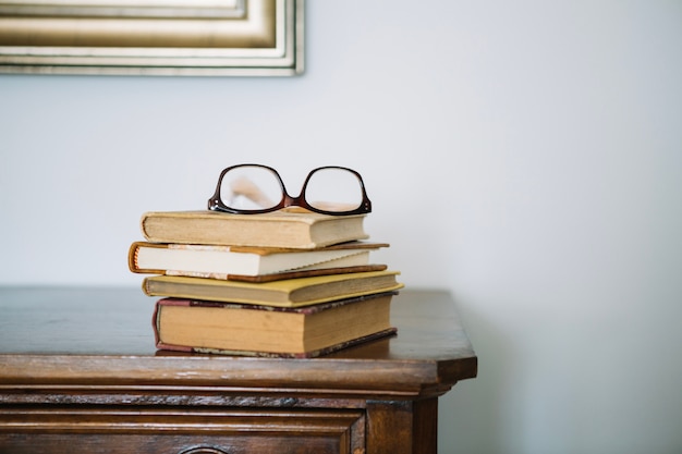 Free photo pile of books and glasses on cabinet