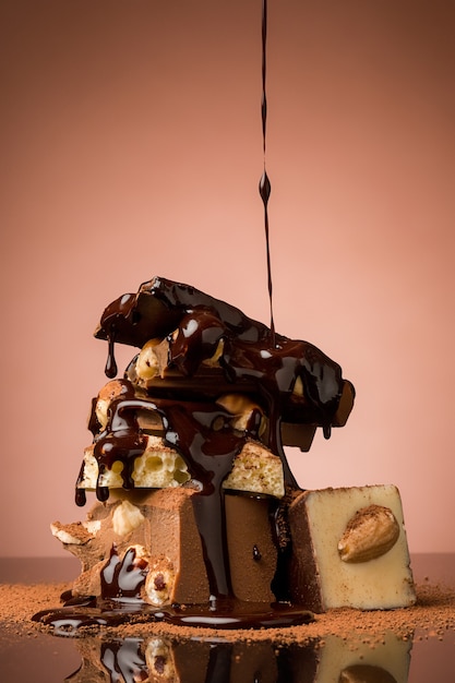 Куча сломанного шоколада на столе на коричневом фоне и брызг горячего шоколада