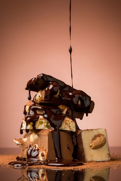 Pile of broken chocolate on table against brown background and hot chocolate spray