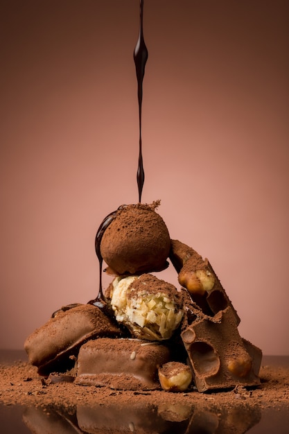 Pile of broken chocolate on table against brown background and hot chocolate spray