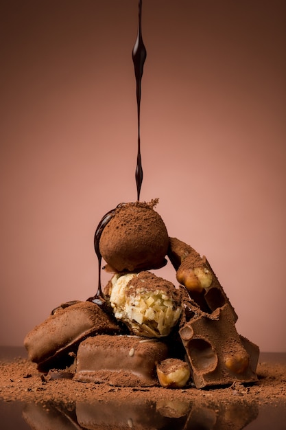 茶色の背景とホットチョコレートスプレーに対してテーブルに壊れたチョコレートの山