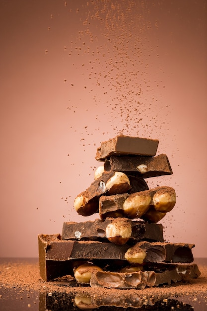 Free photo pile of broken chocolate on table against brown studio background