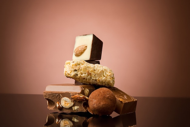 Pile of broken chocolate on table against brown studio background