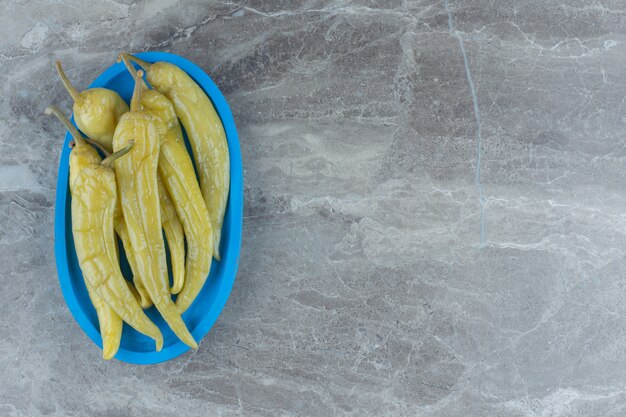 Pile of canned green hot pepper on wooden plate.