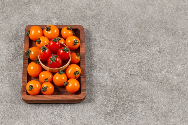 Pile of cherry tomatoes on wooden plate.