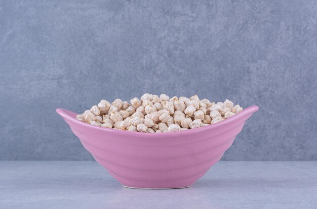 Pile of chickpeas filled in a violet bowl on marble surface