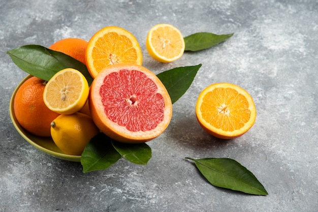 Pile of citrus fruits in bowl over grey table.