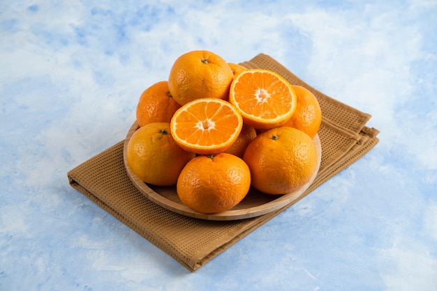 Pile of clementine mandarin n wooden plate over towel