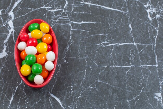 Pile of colorful candies in red bowl. 