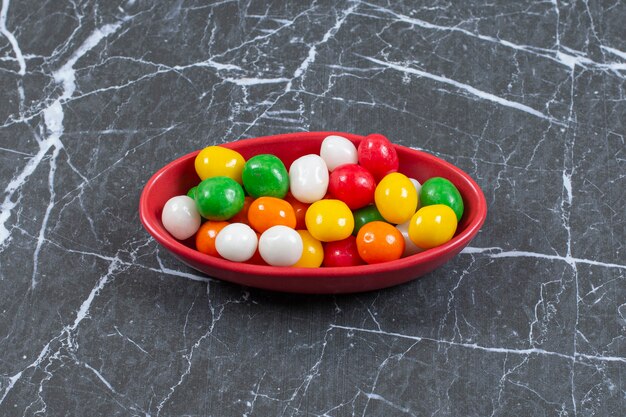 Free photo pile of colorful candies in red bowl.