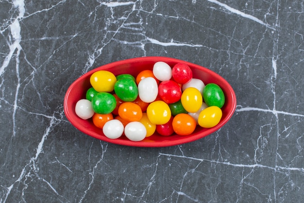 Pile of colorful candies in red bowl. 