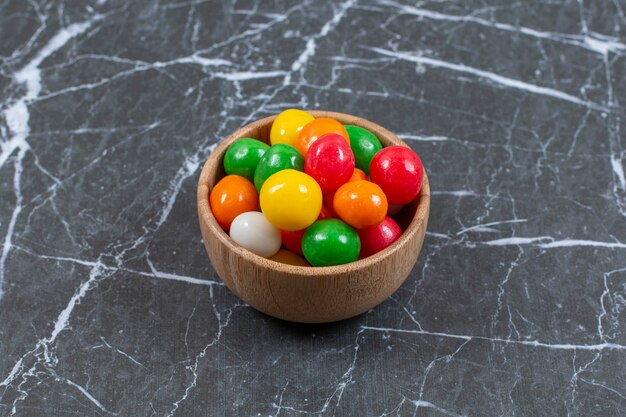pile of colorful candies in wooden bowl. 