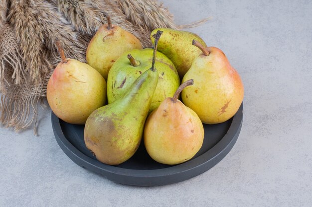 Pile of colorful pears on black plate.