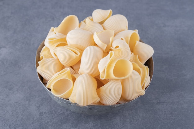 Pile of conchiglie pasta in classic mug.