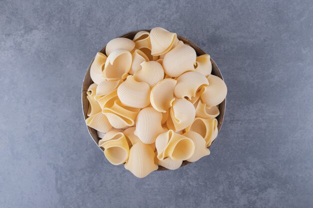 Pile of conchiglie pasta in classic mug.
