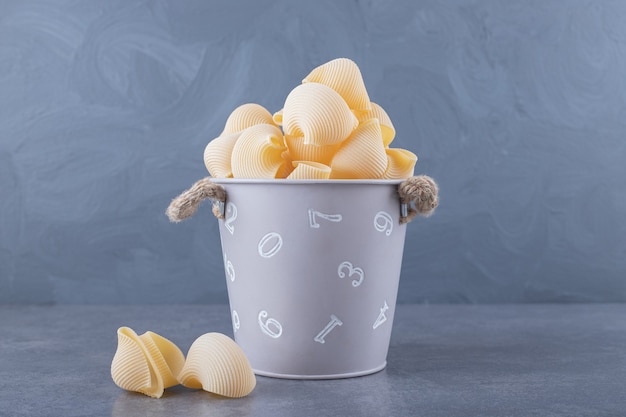 Pile of conchiglie pasta in metal bucket.