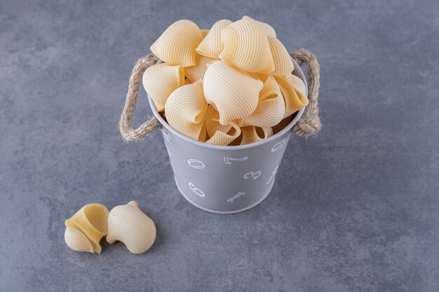 Pile of conchiglie pasta in metal bucket.