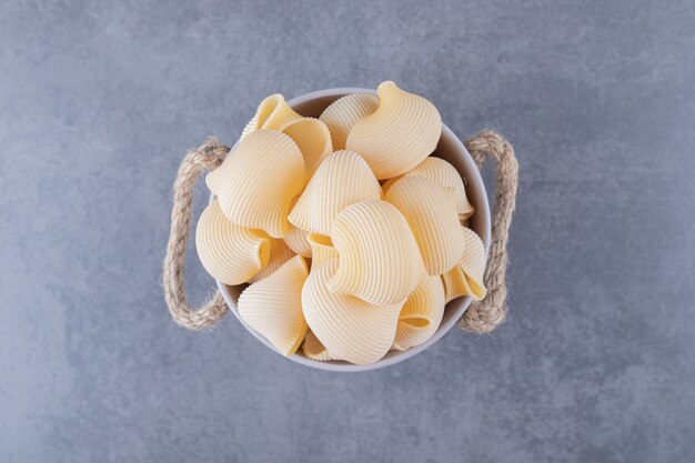 Pile of conchiglie pasta in metal bucket.