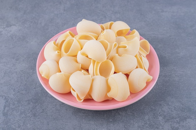 Foto gratuita mucchio di pasta conchiglie sul piatto rosa.
