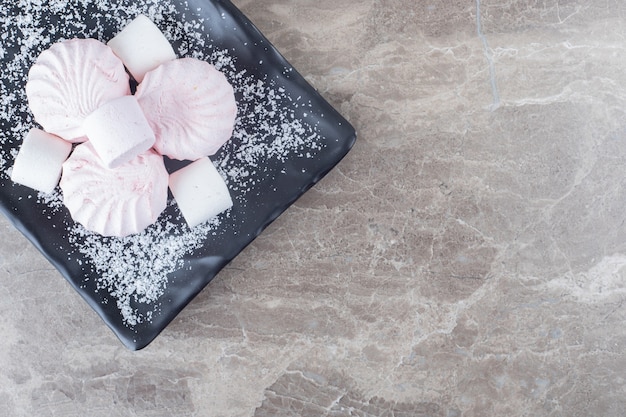 Pile of cookies and marshmallows on a platter on marble surface