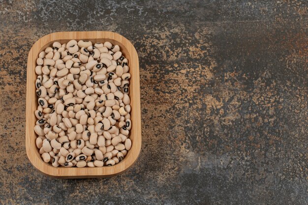 Pile of dry white beans on wooden plate. 