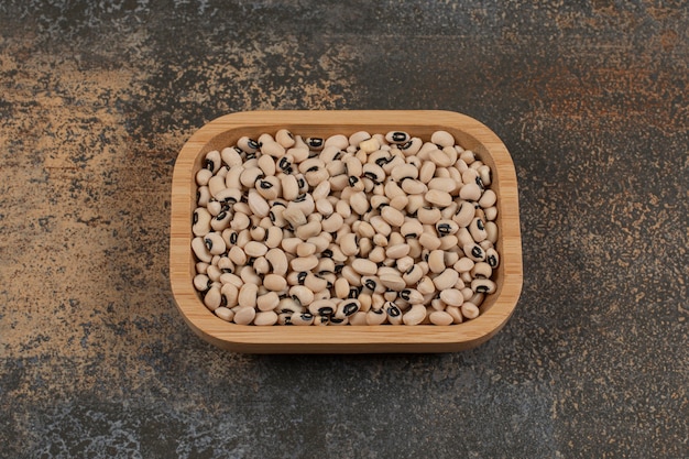 Pile of dry white beans on wooden plate. 