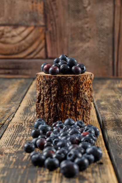 Pile of fresh blueberries in a wooden piece on wooden table