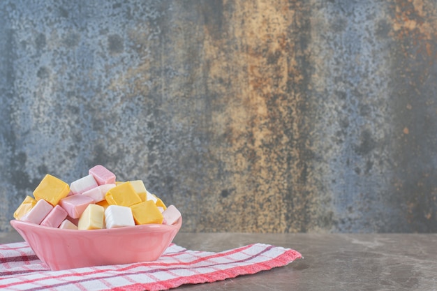 Mucchio di caramelle fresche in forma cubica in ciotola rosa.