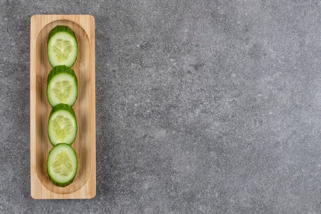 Pile of fresh cucumber slices on wooden board.