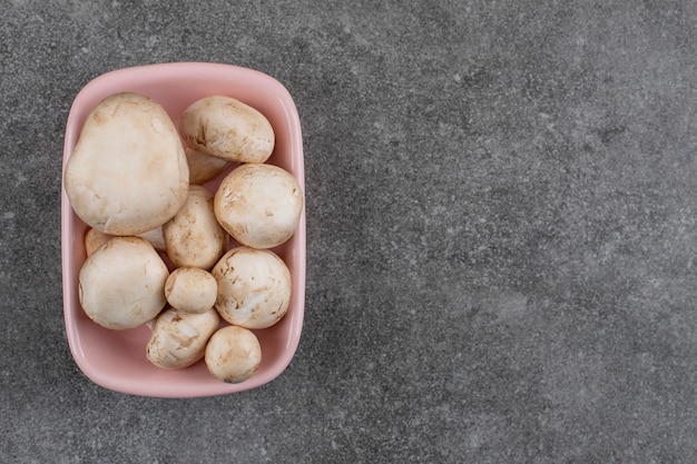 Pile of fresh mushrooms in pink bowl.