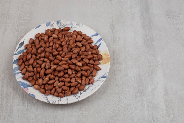 Free photo pile of fresh peanuts on colorful plate.