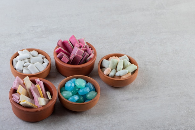 Free photo pile of gums in wooden bowls over grey surface.