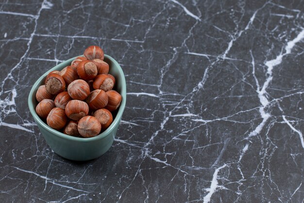 Free photo pile of hazelnuts in blue bowl.