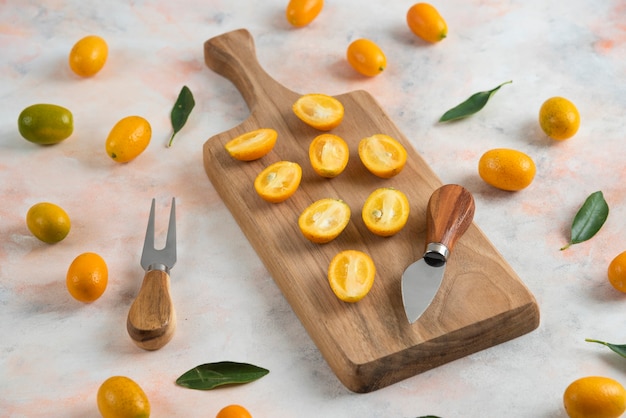 Pile of kumquats, Whole or half cut on wooden cutting board