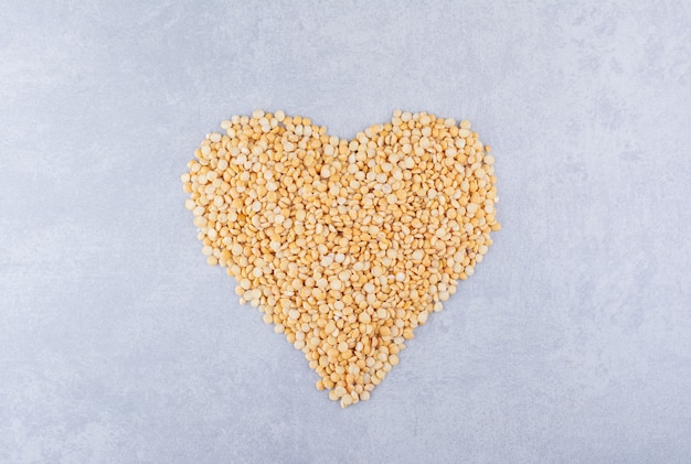 Pile of lentil arranged in a heart shape on marble surface
