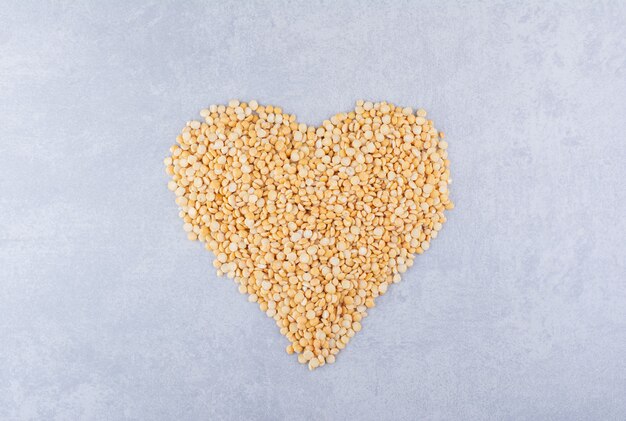 Pile of lentil arranged in a heart shape on marble surface