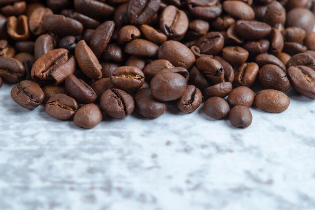 Pile of medium roasted coffee beans on stone surface.