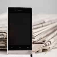 Free photo pile of newspapers with smartphone on it