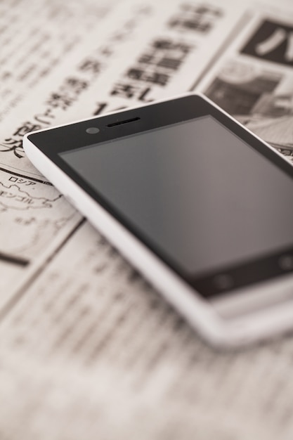 Free photo pile of newspapers with smartphone on it