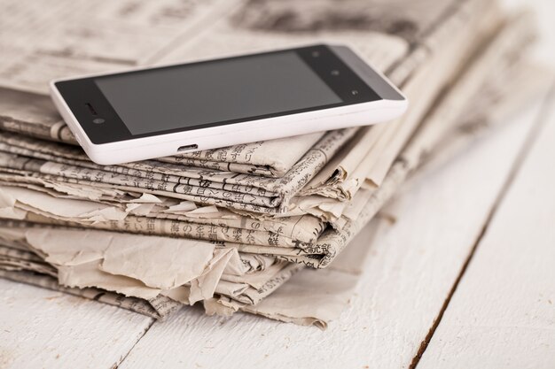 Pile of newspapers with smartphone on it