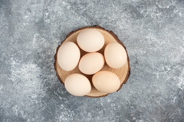 Pile of organic fresh uncooked eggs placed on wood piece.