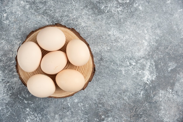 신선한 유기농 계란 더미가 나무 조각에 배치됩니다.
