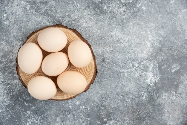 Pile of organic fresh uncooked eggs placed on wood piece.