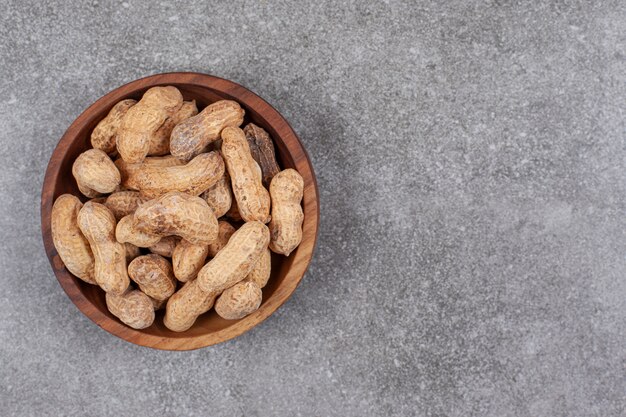 Pile of organic peanuts in wooden bowl