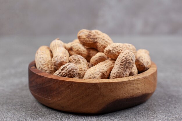 Pile of organic peanuts in wooden bowl