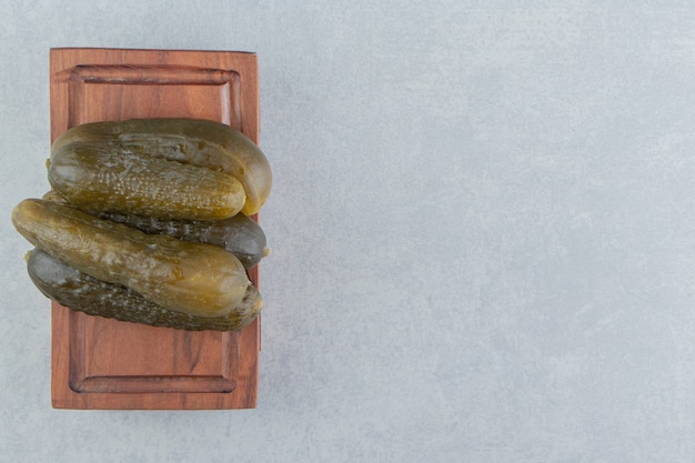 A pile of pickles cucumber on a board, on the marble surface