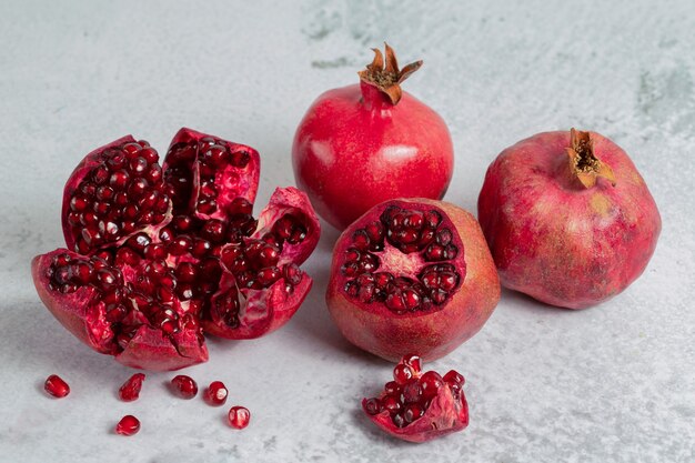 Pile of pomegranates. Sliced or whole pomegranate on grey surface. 