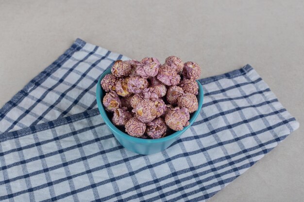 Pile of popcorn candy in a serving size bowl on a towel on marble surface.