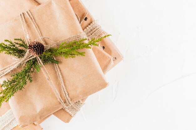 Pile of present boxes in craft paper with coniferous branch