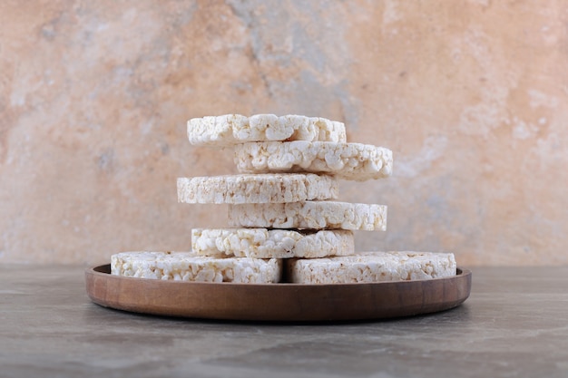 Free photo a pile of puffed rice cakes on the wooden tray, on the marble surface